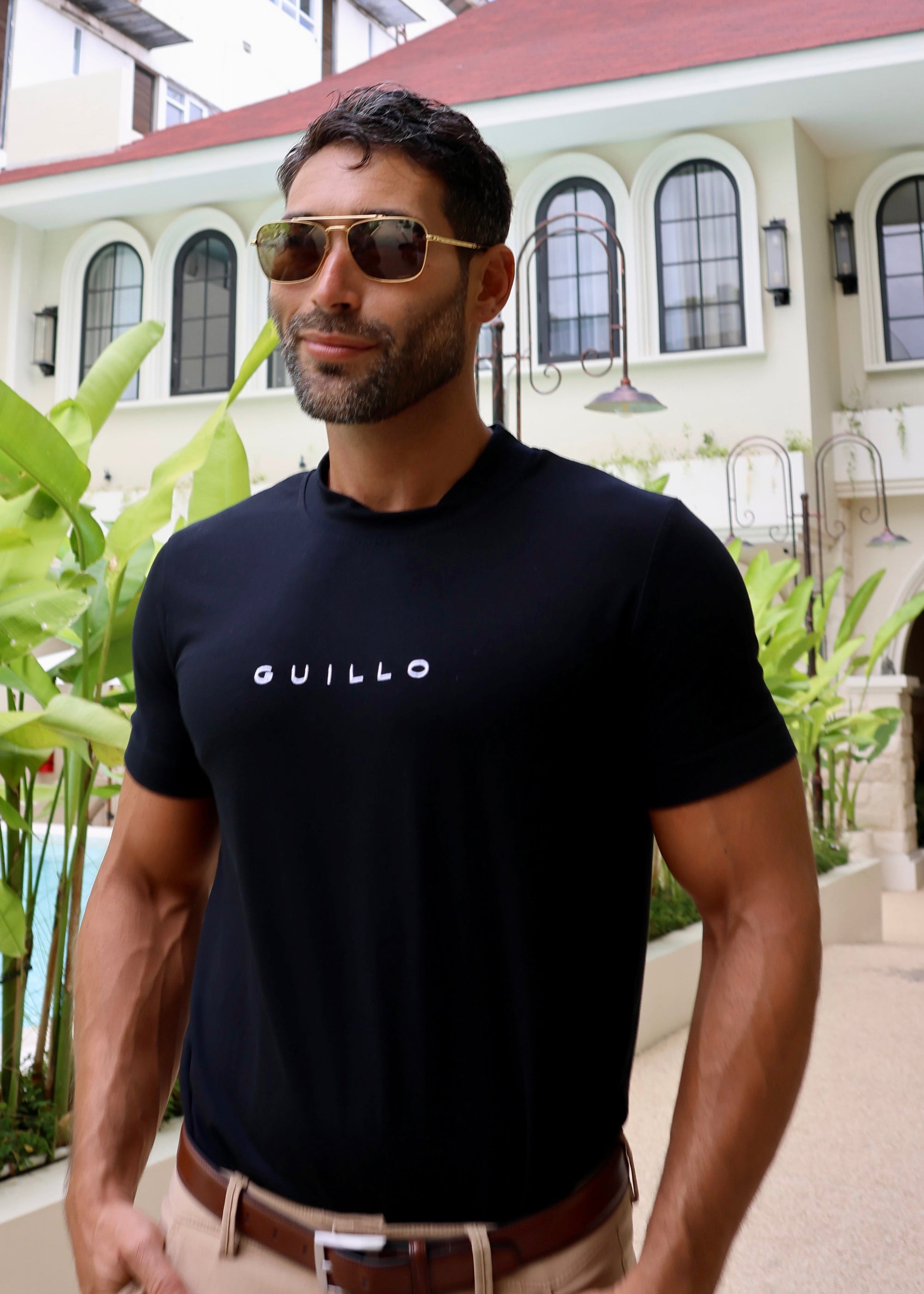 Man wearing a black t-shirt with 'GUILLO' logo outdoors.