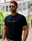 Man wearing a black t-shirt with 'GUILLO' logo outdoors.